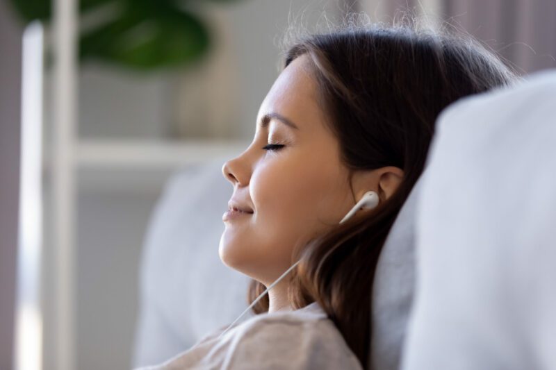 Side view closeup face of woman wearing earphones enjoy music