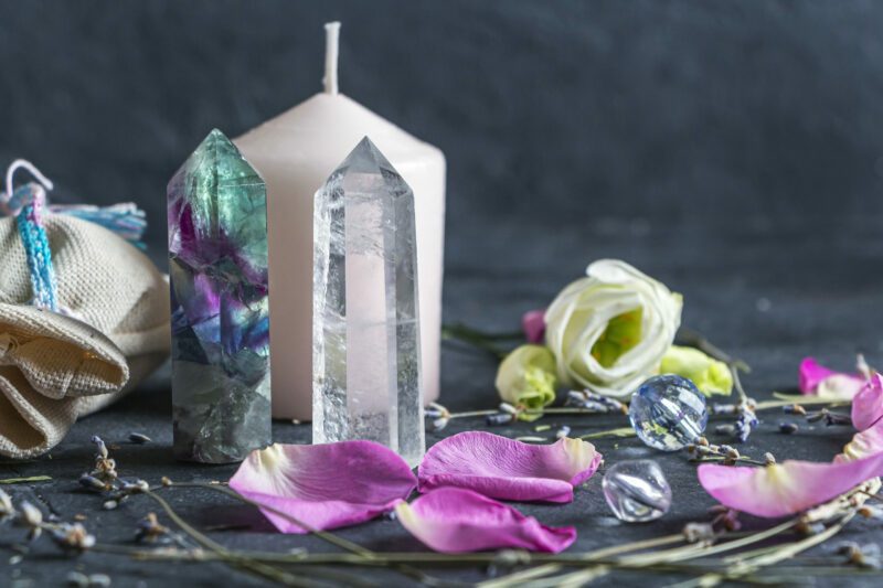 Magic composition with pink candle, crystals, pagan bag and flowers. Esoteric and pagan rituals, witchcraft Wiccan or spiritual practice (healing). Ritual for love. Herbal treatment.